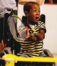 A photo of boy with no forearms playing tennis.